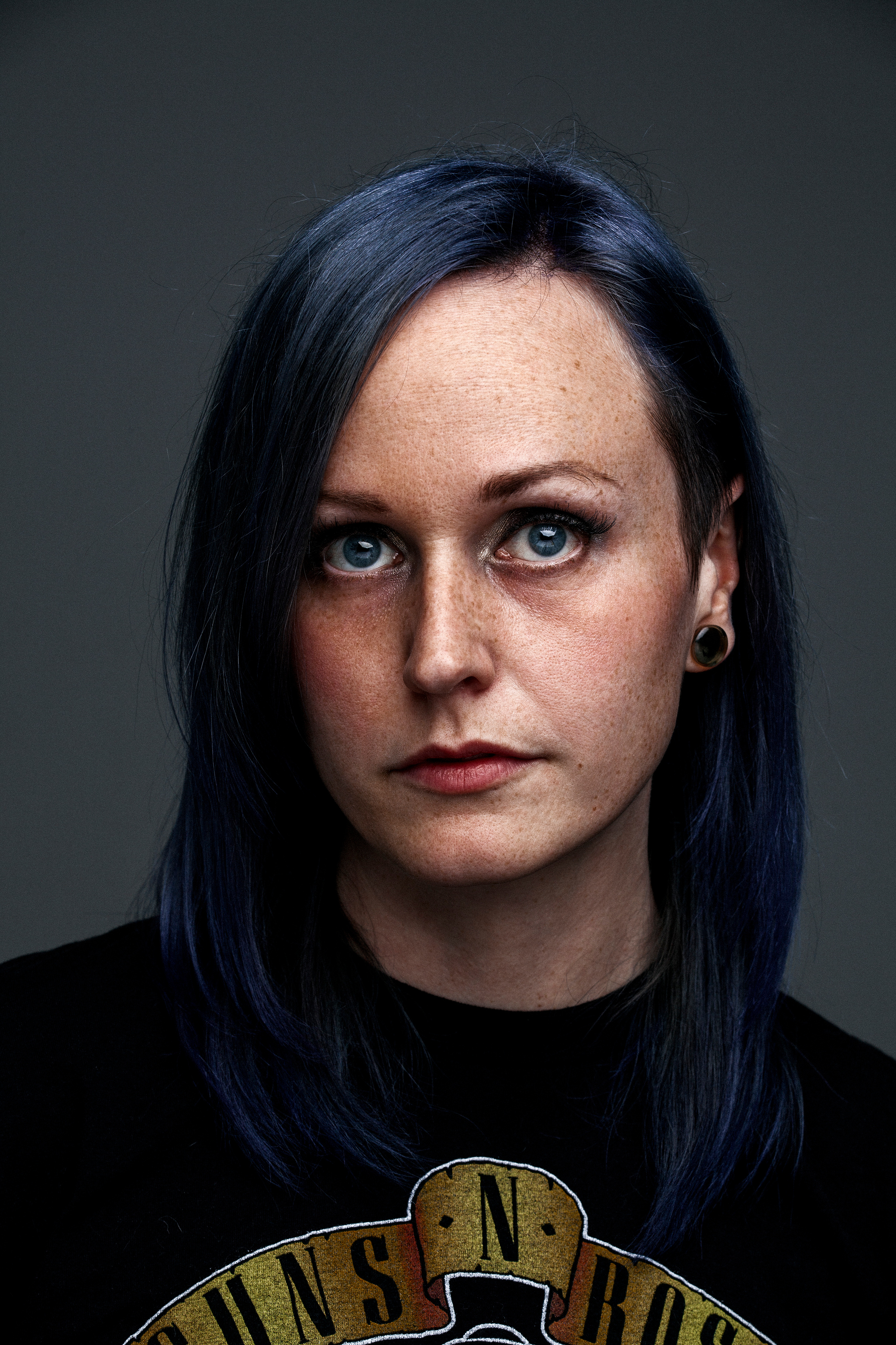 Portrait of artist for a print campaign imagined for tattoo MTL. Grey background, deep color skin tones.